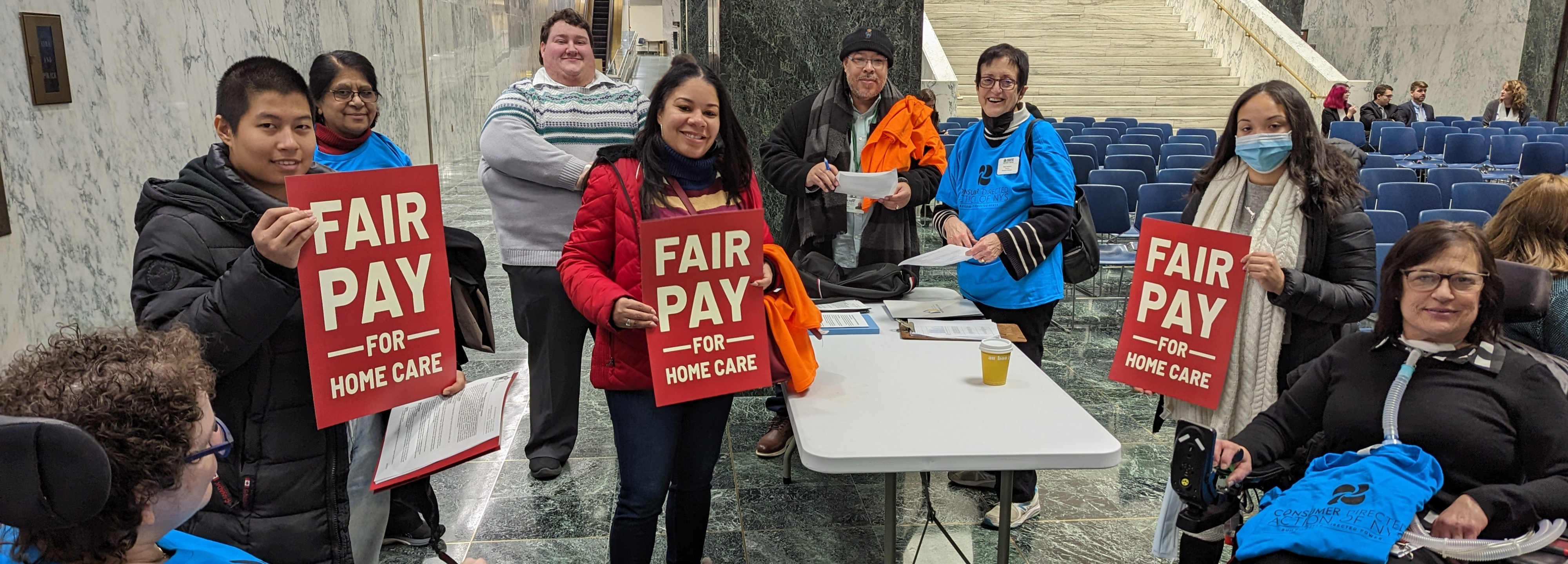 A group of advocates wearing CDANY tshirts holding Fair Pay for Home Care signs.